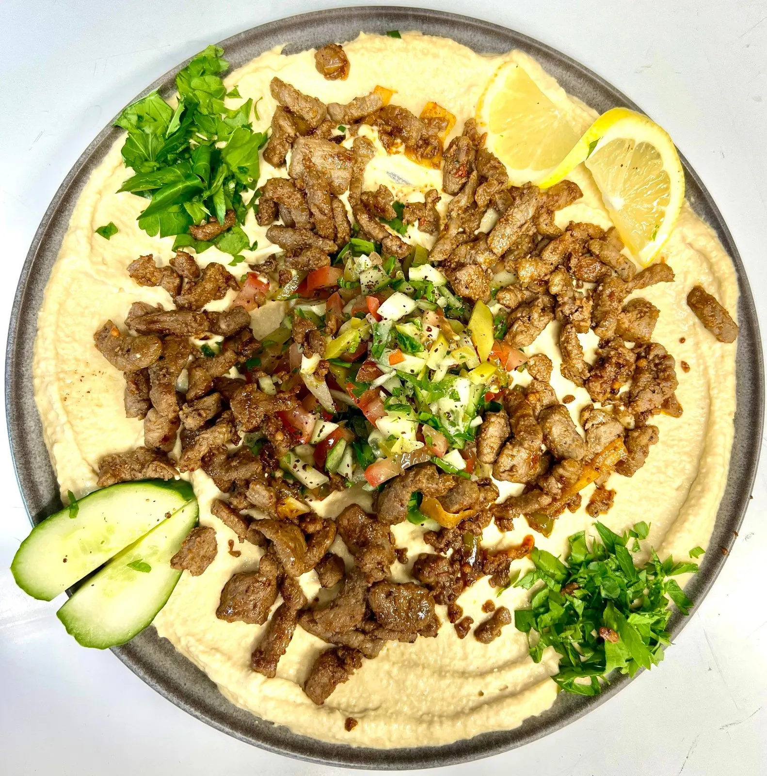 Hummus toppet med biffstrimler, persille, agurk og sitron